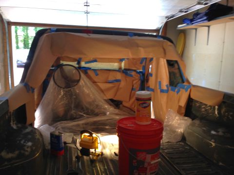 1979 Ford Bronco - The interior of a vehicle, likely a 1979 Ford Bronco, is covered in brown paper and blue tape, preparing for a spray-in bedliner or paint j…