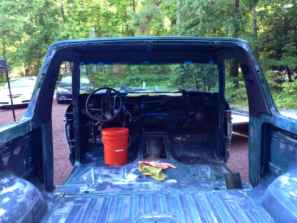 Interior of a disassembled 1979 Ford Bronco, viewed from the rear, showing stripped down interior and bed.