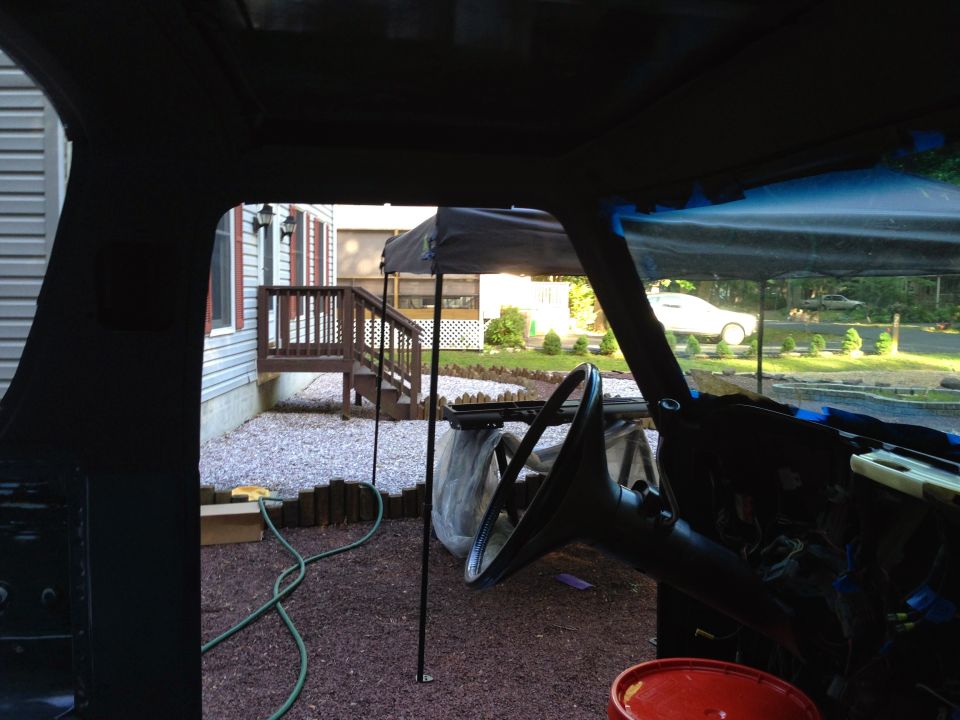 Interior view of a vehicle looking out at a backyard with a deck and a white car.