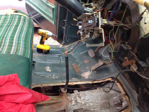 1979 Ford Bronco - The interior of a vintage vehicle, likely a 1979 Ford Bronco, shows the driver's side floorboard, seat, and dashboard area with exposed wir…