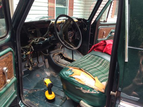 1979 Ford Bronco - The interior of a vintage Ford Bronco is shown with the driver's side door open. The dashboard is partially disassembled, and the driver's…