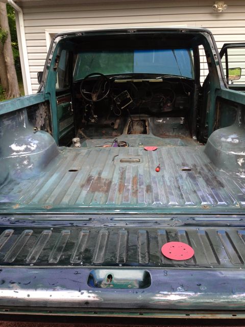 1979 Ford Bronco - The interior and bed of a dark green pickup truck are shown from a rear-facing perspective. The vehicle appears to be undergoing restoratio…
