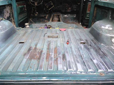 1979 Ford Bronco - The interior of a vintage Ford Bronco is shown with the floor stripped down to the metal, revealing rust and some tools. The dashboard and…