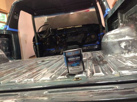 1979 Ford Bronco - The interior and bed of a classic truck are shown, with the bed floor stripped and prepped for coating. A can of "Chassis Saver" paint sits…