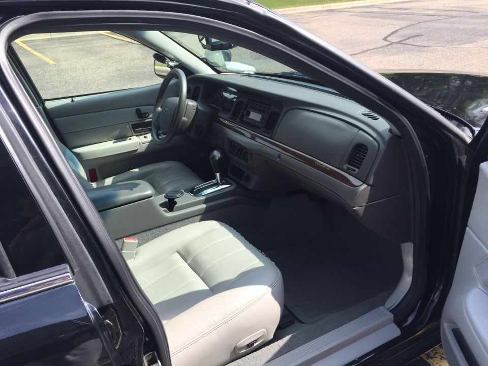 Interior view of a black sedan, showing front seats, dashboard, and steering wheel.
