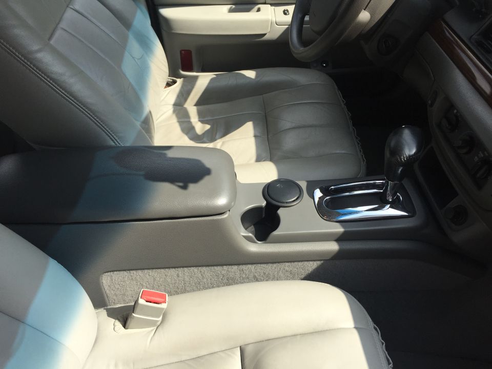 Interior of a car showing center console with gear shifter, cup holder, and armrest.