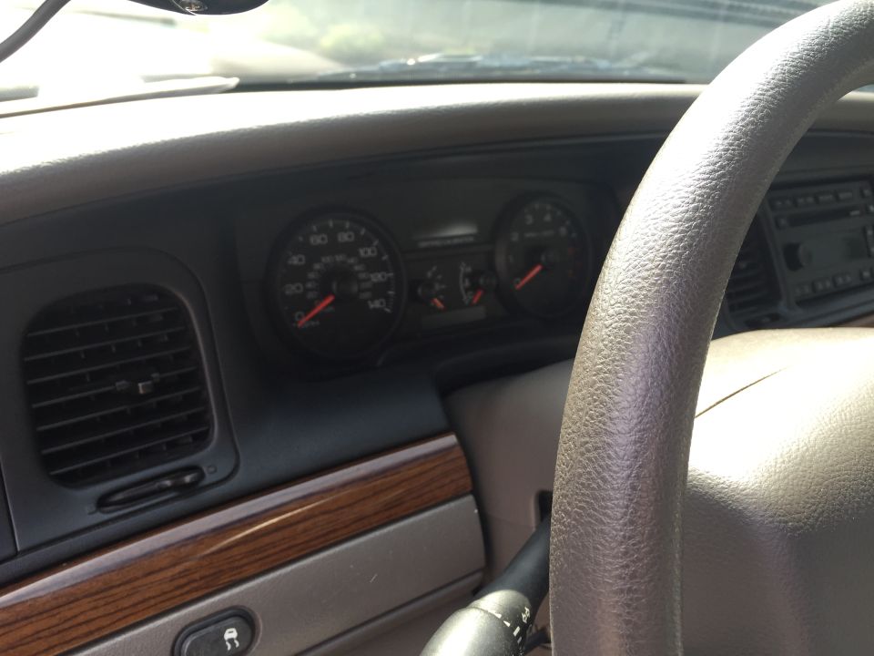 Car dashboard with speedometer, tachometer, air vent, and steering wheel.