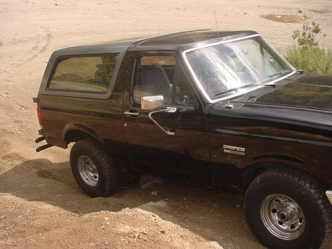1988 Ford Bronco - 1988 Ford Bronco parked on a dirt surface, showing its side profile and removable hardtop.