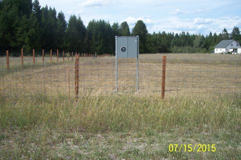 1989 Ford Bronco - A utility box stands in a fenced-off field with a line of trees in the background. A white house is visible in the distance on the right si…