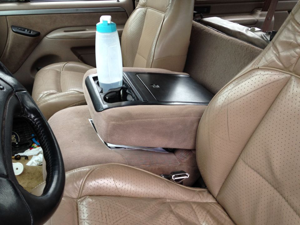 Tan interior with center console holding a clear water bottle, viewed between the front seats