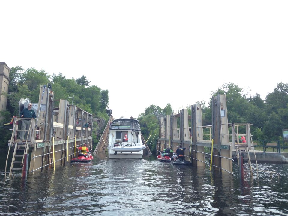 Cabin cruiser boat in a lock with two jet skis.