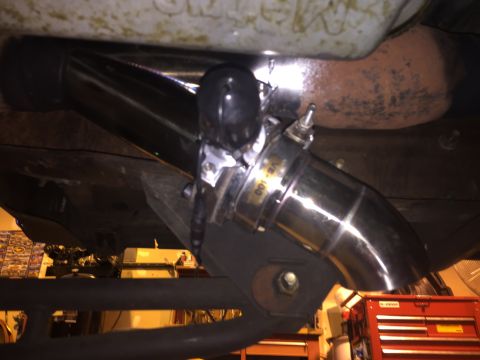 1992 Ford Bronco - The underside of a vehicle shows a polished metal exhaust pipe system with a clamp labeled "VB-100". A rusty exhaust manifold is visible ab…