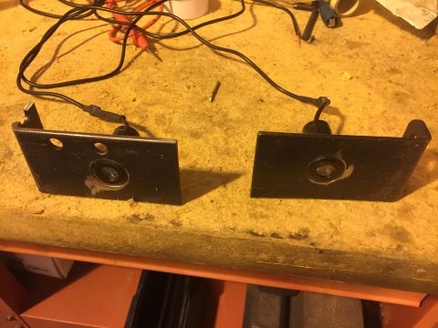 1992 Ford Bronco - Two black metal brackets, each with a small circular lens, are mounted on a yellow surface. Wires are connected to the back of each bracket.