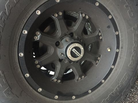1992 Ford Bronco - A close-up view of a black aftermarket wheel and tire on a vehicle. The wheel has a WARN locking hub in the center.