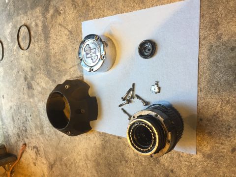 1992 Ford Bronco - Disassembled parts of a 4x4 automatic locking hub are laid out on a concrete surface with a white paper towel. Visible parts include a chro…