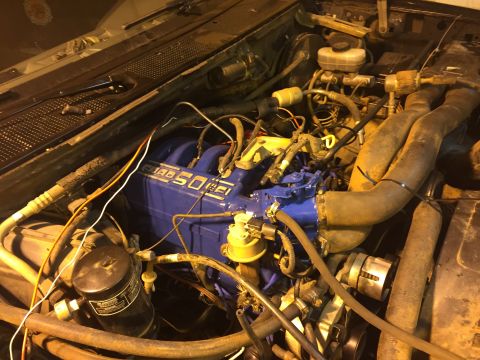 1992 Ford Bronco - The blue engine of a 1992 Ford Bronco is visible, with various hoses, wires, and engine components surrounding it. The engine has "5.0 EFI"…