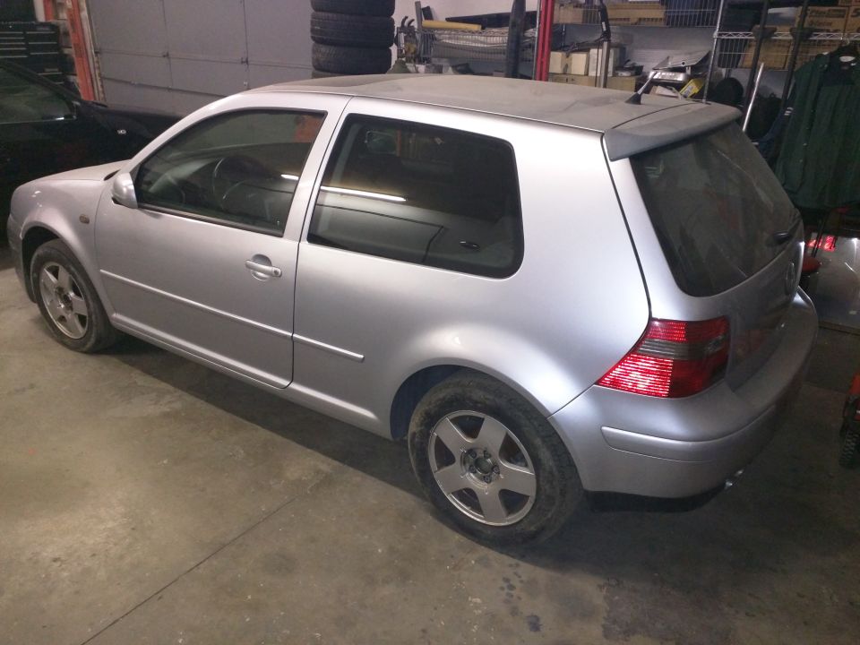 Silver 3-door hatchback, rear passenger side view, in a garage.