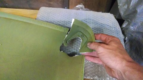 1992 Ford Bronco - A hand holds a broken, green-painted piece of what appears to be a vehicle body panel. The piece has a curved edge and a section with a rai…