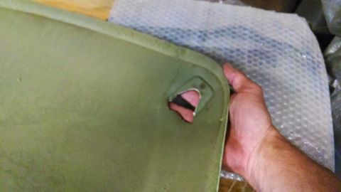 1992 Ford Bronco - A hand holds a green, possibly fiberglass, panel with a triangular cutout revealing a pink and black interior component. The panel appears…