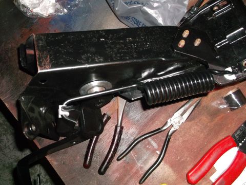 1967 Ford Mustang - A black metal automotive part, possibly a component from a vehicle's suspension or linkage system, is shown with tools.