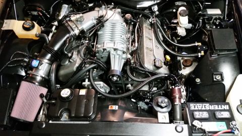 2004 Mercury Grand Marquis - Close-up view of a modified V8 engine, a prominent supercharger and aftermarket air intake system.