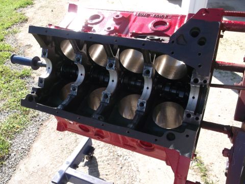 1957 Ford Custom Sedan - A red engine block with visible crankshaft bearings is shown mounted on a stand outdoors.