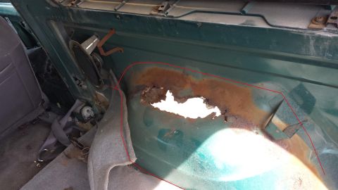 1995 Ford Bronco - The interior of the vehicle shows extensive rust damage and a hole in the rear body panel.