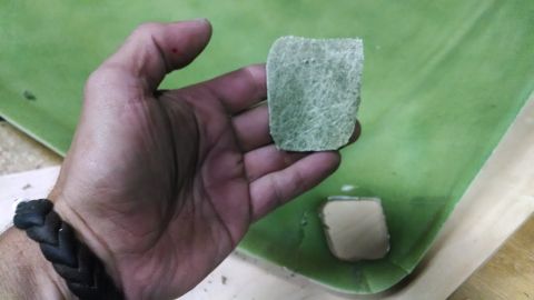 1992 Ford Bronco - A hand holds a sample of fiberglass material against a larger green surface, with another piece visible below.