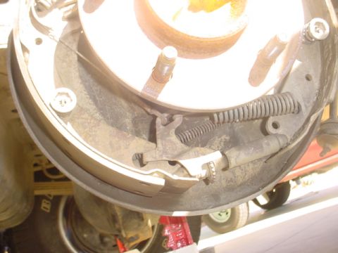 1988 Ford Bronco - Close-up view of a vehicle's rear drum brake assembly, showing internal components like springs and brake shoes.