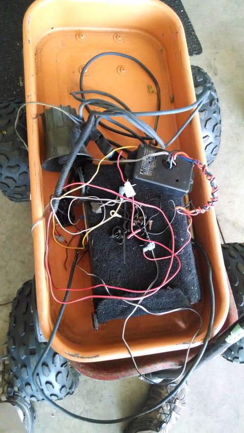 1994 Ford Bronco - This is an overhead view of an orange wagon filled with wires and electronic components. The wagon has four black tires and appears to be i…