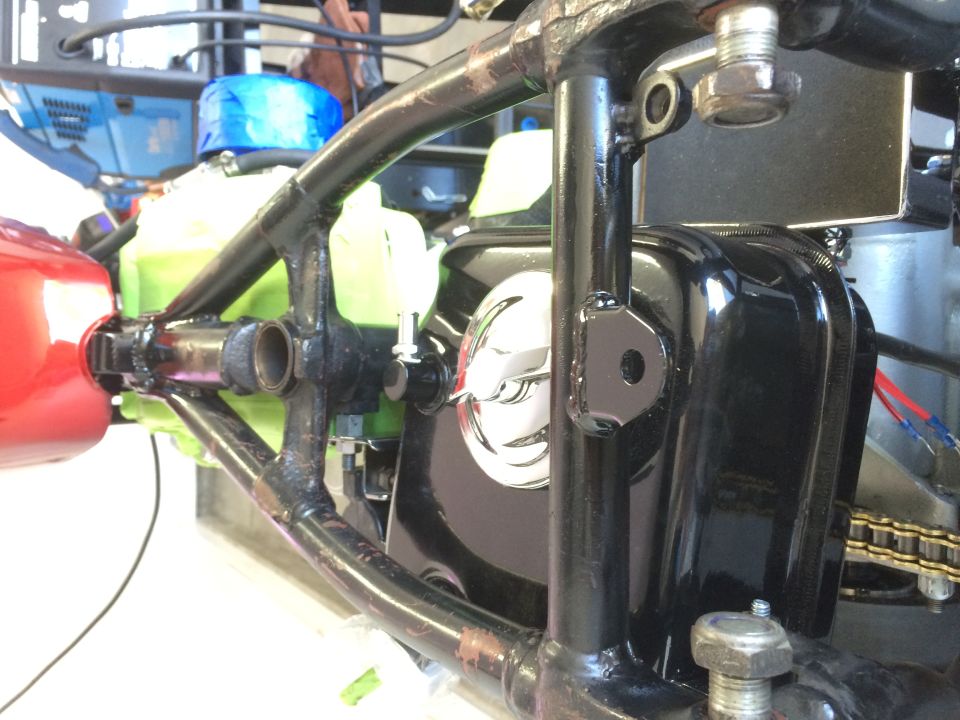 Motorcycle engine and frame details, black engine cover, green reservoir
