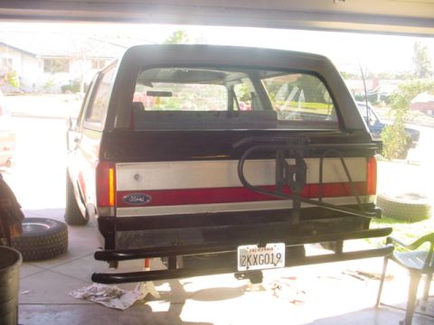 1988 Ford Bronco - The rear of a Ford Bronco is shown, a red and white stripe on the tailgate and a spare tire mount.