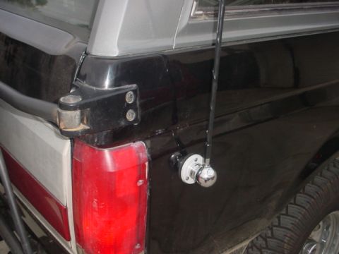 1988 Ford Bronco - Close-up view of the rear corner of a black pickup truck, showing a CB antenna and taillight.