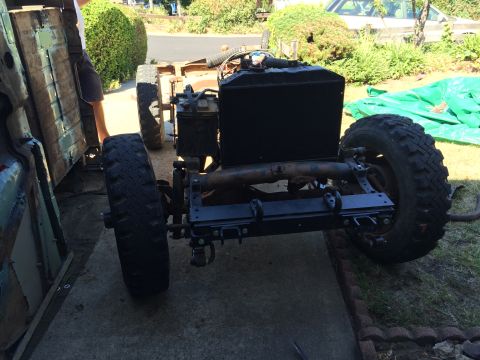 1946 Jeep Willys - The rear chassis and large tires of a vehicle undergoing restoration are visible. A black radiator and engine components are mounted on the…