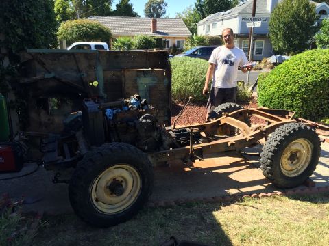 1946 Jeep Willys - A man stands next to the disassembled frame and body of an old Jeep CJ5, which is undergoing restoration. The vehicle's engine and suspensi…