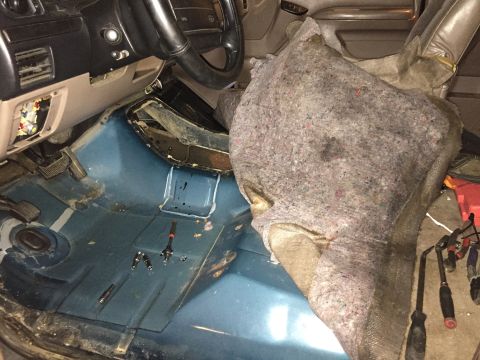 1994 Ford Bronco - The interior of a vehicle is shown with the driver's side dashboard, steering wheel, and floor visible. A large piece of insulation or padd…