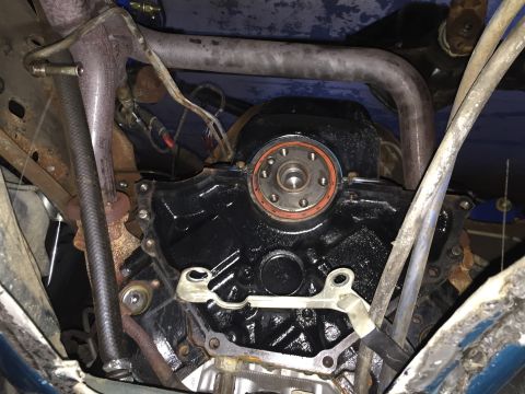 1994 Ford Bronco - A close-up view of the rear of a black engine block, likely from a 1994 Ford Bronco, showing a newly installed rear main seal. Various hose…