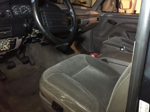 1994 Ford Bronco - The interior of a 1994 Ford Bronco shows the driver's side seat, dashboard, steering wheel, and center console. The dashboard is partially…