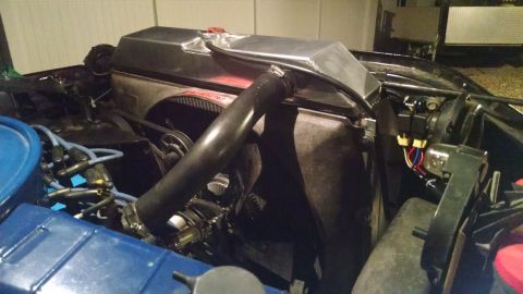 1979 Ford F-150 - The engine bay of a classic Ford F-150 shows a polished aluminum radiator with a black hose connected to it. Various engine components incl…