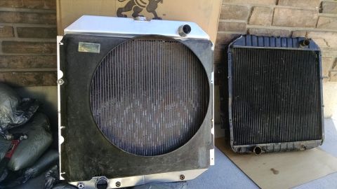 1979 Ford F-150 - Two radiators are shown side-by-side outdoors. The radiator on the left is larger and appears to be made of aluminum, while the one on the…