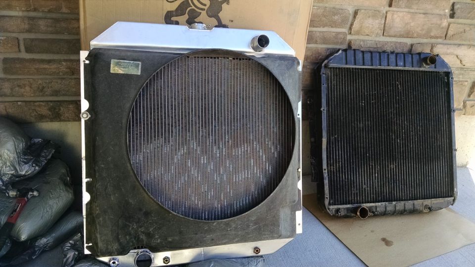 Two radiators, one aluminum and one black, displayed outdoors.