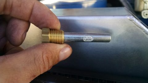 1979 Ford F-150 - A hand holds a brass fitting with a metal rod extending from it, showing the embossed text "O-A" on the rod. The fitting is threaded and ap…