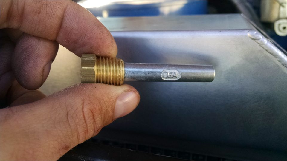 Close-up of a hand holding a brass fitting with a metal rod marked "O-A".
