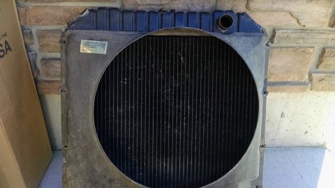 1979 Ford F-150 - A front view of a radiator for a 1979 Ford F-150. The radiator has a black grille and a blue top mounting bracket.