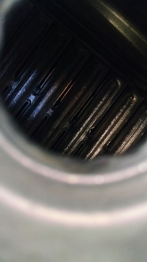1979 Ford F-150 - A close-up, angled view inside a dark, metallic component with parallel ridges and slots. The surface appears oily and reflects light, sugg…