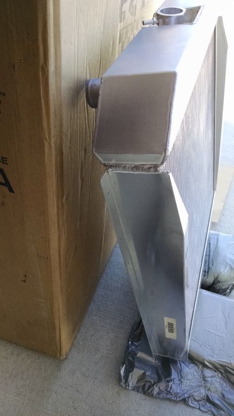 1979 Ford F-150 - A new aluminum radiator is shown next to a large cardboard box. The radiator has a shiny metal finish and visible welding seams.