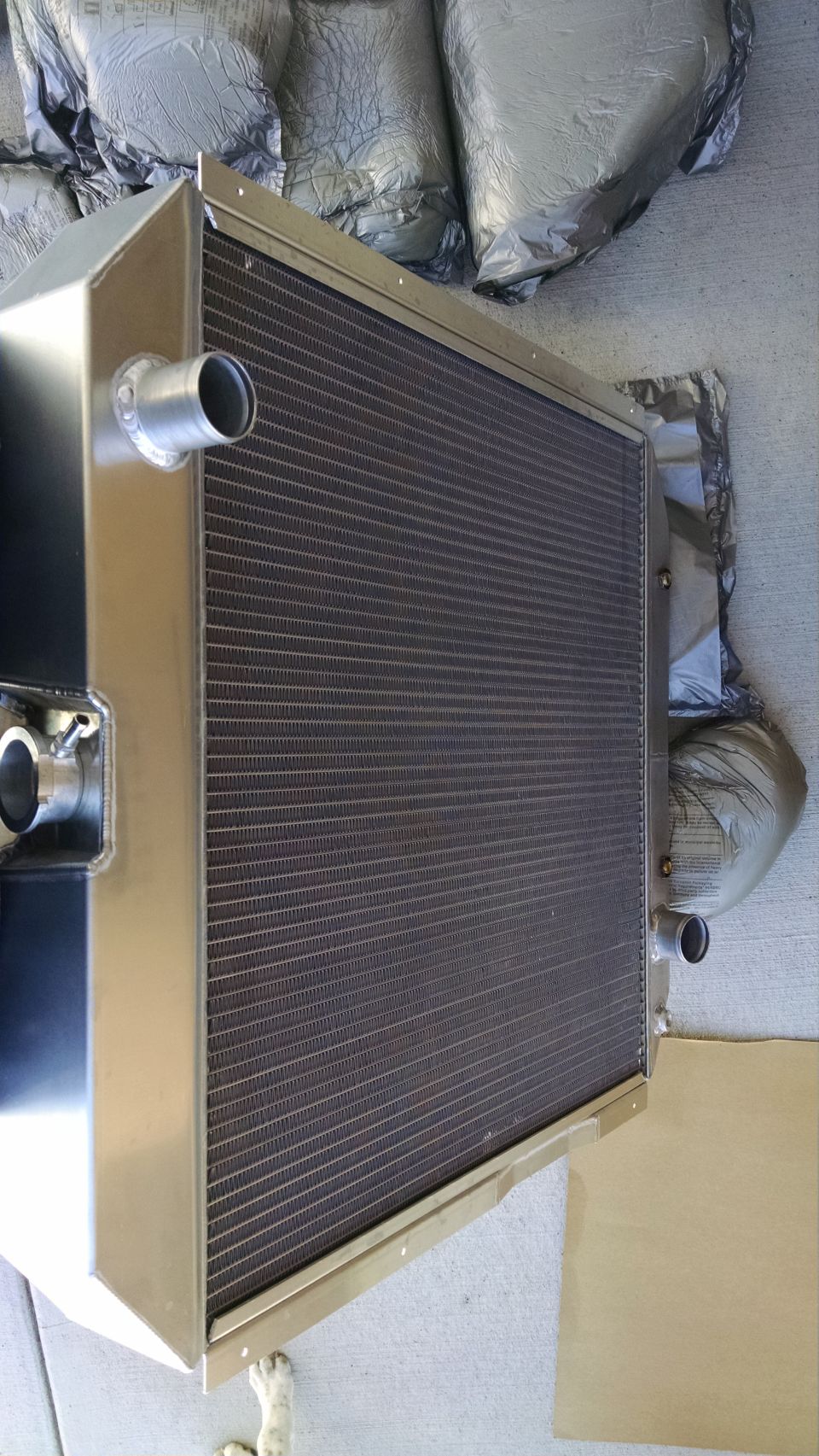 Aluminum automotive radiator with inlet and outlet necks laid on cardboard