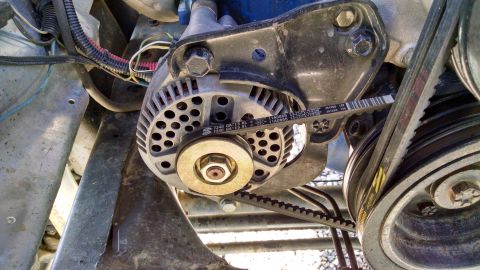 1979 Ford F-150 - A close-up view of an alternator and serpentine belt system on a vehicle engine. Text on the belt reads "7340 GATES XL 11A0865".