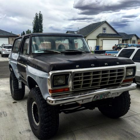 1979 Ford Bronco - A lifted 1979 Ford Bronco with a black hood and fenders, parked in a driveway with houses and other vehicles in the background. The vehicle…