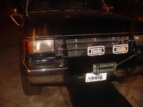 1988 Ford Bronco - Front view of a black Ford Bronco, equipped with auxiliary Hella lights and a winch.